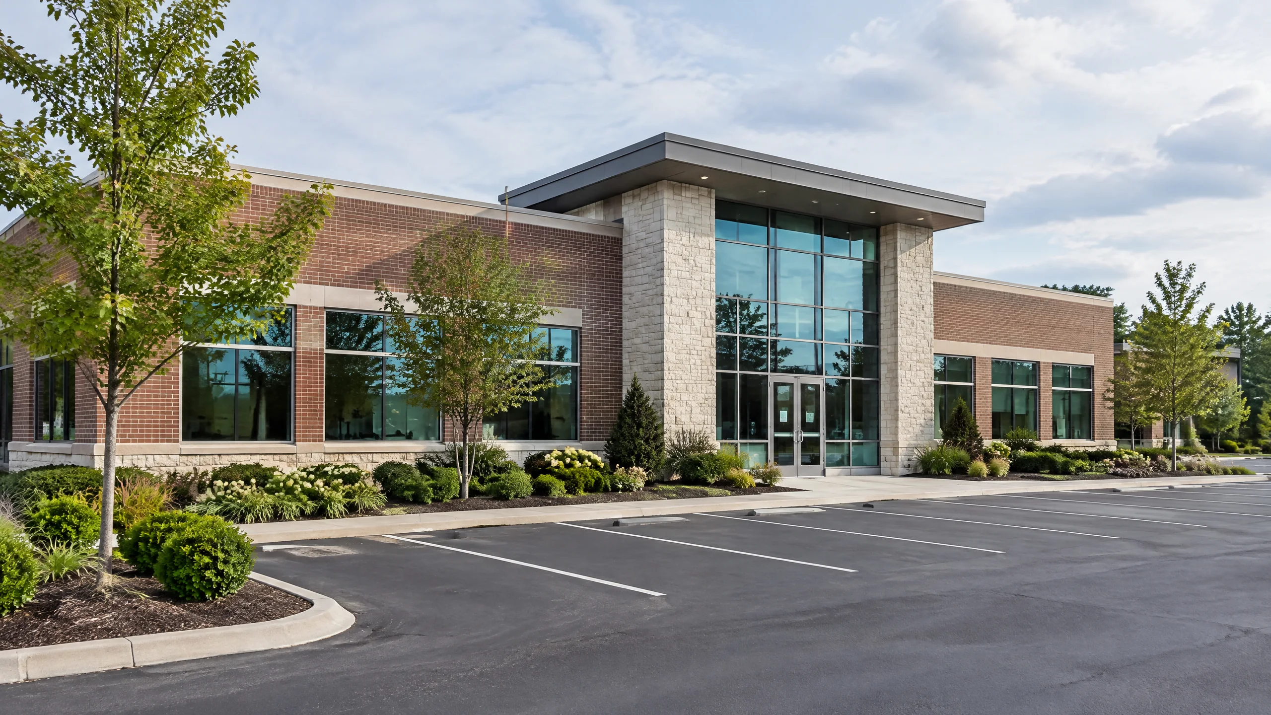 AI-generated representative view of a low-rise commercial office building with brick and glass entrance and empty parking bays
